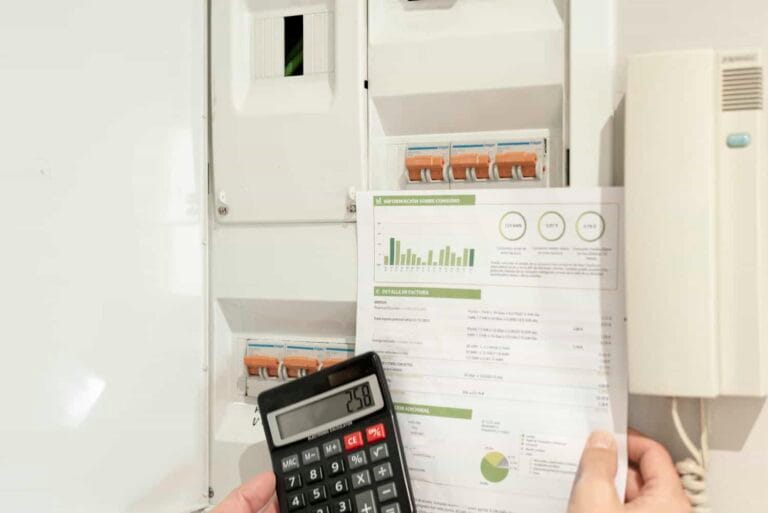 a hand holding an electricity bill and calculator